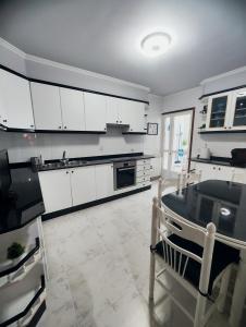 a kitchen with white cabinets and a table in it at Piso Pauser in Puentecesures