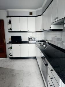 uma cozinha branca com armários brancos e um lavatório em Piso Pauser em Puentecesures