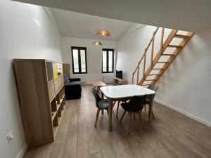 ein Zimmer mit einem Tisch, Stühlen und einer Treppe in der Unterkunft Grand Studio Duplex Stade France in Aubervilliers