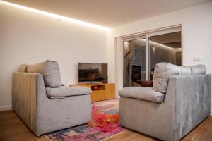 ein Wohnzimmer mit zwei Stühlen und einem Fernseher in der Unterkunft Apartamento Fragosa - Vieira's Mar in Póvoa de Varzim + 31 Fotos