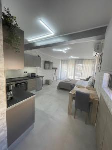 eine Küche und ein Wohnzimmer mit einem Tisch und einem Sofa in der Unterkunft AVR Airport Deluxe Suites 6 in Markopoulo
