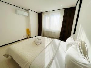 1 dormitorio con 2 camas blancas y ventana en Highvill Park 2-Room Apartments, en Astana