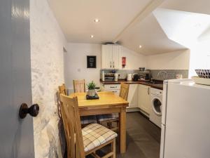 a kitchen with a wooden table and chairs and a refrigerator at Arthurs Cottage in Tywyn