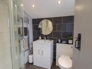 a bathroom with a toilet and a sink and a mirror at Arthurs Cottage in Tywyn +17 photos