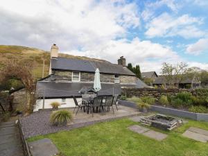 a house with a patio with a table and chairs at Arthurs Cottage in Tywyn