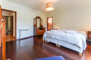 a bedroom with a white bed and a wooden floor at Casa do Ourives in Charneca