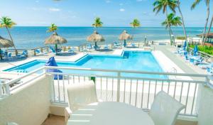 a balcony with a swimming pool and the ocean at Caloosa Cove Resort - With Full Kitchens in Islamorada