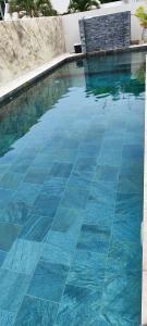 a swimming pool with blue tiles on the floor at Villa Mary Guest House in Saint-André