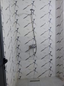 La salle de bains est pourvue d'une douche et d'un mur en briques blanches. dans l'établissement Lotissement melouiya GUERCIF Maroc, à Guercif