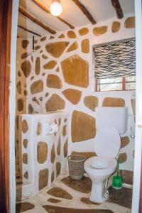 La salle de bains est pourvue d'un mur en pierre et de toilettes. dans l'établissement Kijani Cottages - In Diani, à Diani Beach
