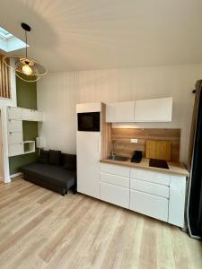 eine Küche mit weißen Schränken und einem Sofa in einem Zimmer in der Unterkunft Studio "Cocon Suspendu" 4 pers-Terrasse-Clim-Barbecue-15km des plages in Montpellier