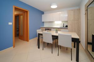a kitchen with a dining table and white chairs at Garden Palace Pool Deluxe Apartment in Umag