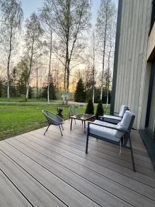 a wooden deck with a couch and chairs on it at Albatross Getaway by the sea, SPA and forest with a Terrace in Ķesterciems