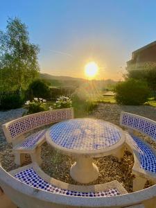 uma mesa e dois bancos com o pôr-do-sol ao fundo em Casa La Xana del Valle em Llanes