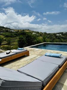 a swimming pool with two lounge chairs next to it at Villa Kotseli - Sea View, Pool, Sunsets in Andros