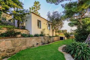 a house with a stone wall and a yard at La Picolla Bellezza in Mandelieu-la-Napoule