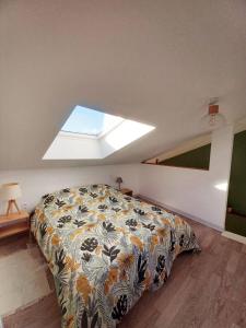 1 dormitorio con 1 cama con colcha y ventana en La busco loge, en Chinon