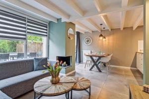 uma sala de estar com um sofá e uma mesa em Luxe Bos bungalow met Airco em Posterholt