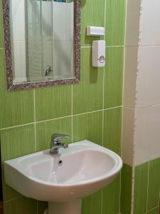 a green bathroom with a sink and a mirror at Esmeralda Apartaments in Sarandë +25 photos