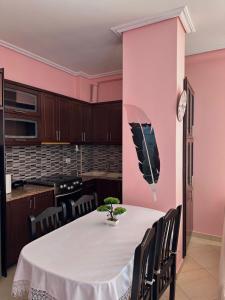 ein Esszimmer mit einem Tisch und rosa Wänden in der Unterkunft Esmeralda Apartaments in Sarandë