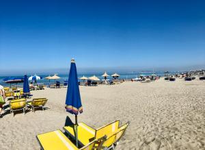 a beach with chairs and a blue and yellow umbrella at Beach Apartments Durres in Durrës