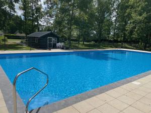 uma grande piscina azul com uma casa ao fundo em Luxe Bos bungalow met Airco em Posterholt
