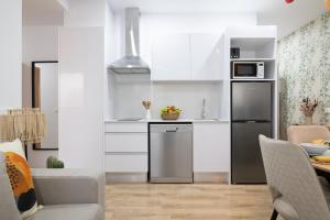 kuchnia z białymi szafkami i lodówką ze stali nierdzewnej w obiekcie Dorm4You Arena Family 13 w Walencji