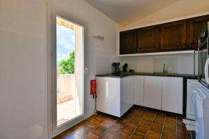 a kitchen with white cabinets and a large window at Charmante maison Porticcio in Porticcio