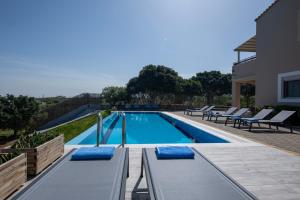 uma piscina com almofadas azuis numa casa em Four Seasons private villa - seaview - big heated pool - gym - sport activities em Gouves