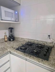 a stove top in a kitchen with a microwave at Souza Lofts Centro Praça Tiradentes in Teófilo Otoni