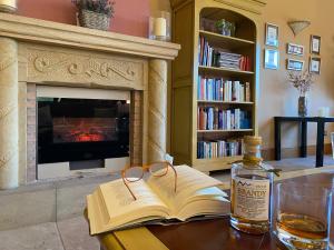 un libro y una botella de whisky en una mesa con chimenea en Hotel Finca Malvasia en Cabezón de Liébana