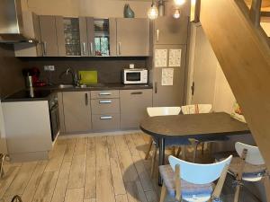a small kitchen with a table and a microwave at Gîte les tilleuls in Ronquerolles