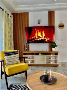 a living room with a fireplace with a yellow chair and a table at Appartement meublé 2 Chambres, Salon - Bastos, Ambassade du Tchad, Yaoundé, CMR in Mbala