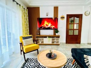 ein Wohnzimmer mit einem TV und einem gelben Stuhl in der Unterkunft Appartement meublé 2 Chambres, Salon - Bastos, Ambassade du Tchad, Yaoundé, CMR in Mbala