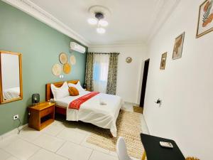 1 dormitorio con cama, mesa y espejo en Appartement meublé 2 Chambres, Salon - Bastos, Ambassade du Tchad, Yaoundé, CMR, en Mbala