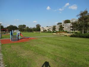 un parque con parque infantil en un campo de césped en Appartement AanZee en Hoek van Holland