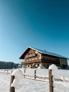 a building in the snow with a fence at Chalet-Apartments Am Schmiedhof in Vogtareuth
