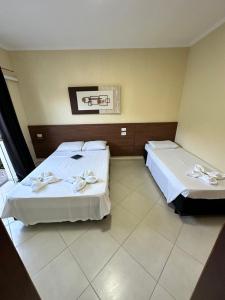 a hotel room with two beds with towels on them at Werneck Residence Suites in Ubatuba
