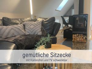 un sofá de cuero negro en una sala de estar con TV en Ferienwohnung Auszeit Dachstudio, en Sulzburg