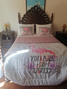 a bed with a sign that says you are loved at Propriedade dos Seixos in Moledo