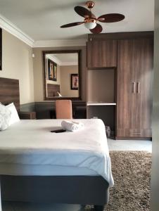 um quarto com uma cama e uma ventoinha de tecto em Sunrise Boutique Hotel em Witbank