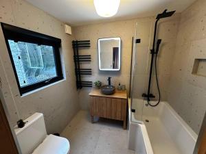 La salle de bains est pourvue de toilettes, d'une baignoire et d'un lavabo. dans l'établissement Pass the Keys Acorn Lodge · Luxury Retreat In a Stunning Oasis With Hot Tub, à Market Drayton