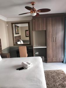 um quarto com uma cama, uma ventoinha e um espelho. em Sunrise Boutique Hotel em Witbank