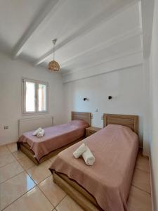 2 bedden in een witte kamer met een raam bij Villa Tramonto in Lévki
