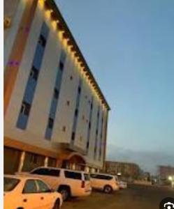 two cars parked in front of a large building at نجمة سماء ينبع للشقق المفروشة in Madīnat Yanbu‘ aş Şinā‘īyah