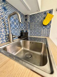 a stainless steel sink in a kitchen with blue and white tiles at Appartement en rez-de-jardin in Baie Nettle