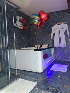 uma casa de banho com uma banheira, uma televisão e um balão em La Dream Night em Pontault-Combault