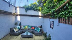eine Terrasse mit einem Sofa und einem Tisch mit Kissen in der Unterkunft Whole House with a private garden and terrace, central Brighton in Brighton & Hove