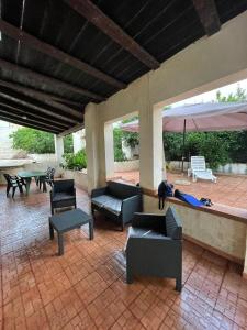 een patio met stoelen en tafels en een parasol bij Villa Pappafico in Triscina
