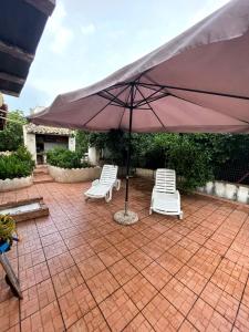 2 stoelen en een parasol op een bakstenen patio bij Villa Pappafico in Triscina